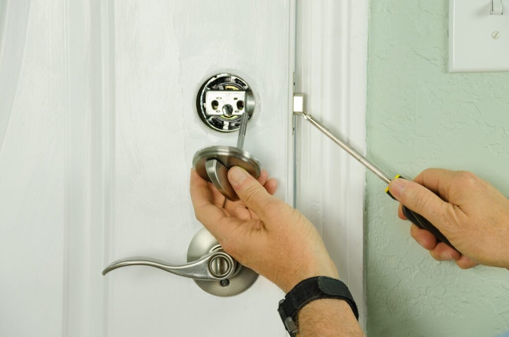 Locksmith installing a new deadbolt lock on a white residential door with a screwdriver
